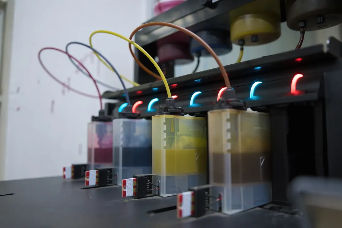 Tanques de tinta de colores conectados por mangueras a un equipo de impresión
